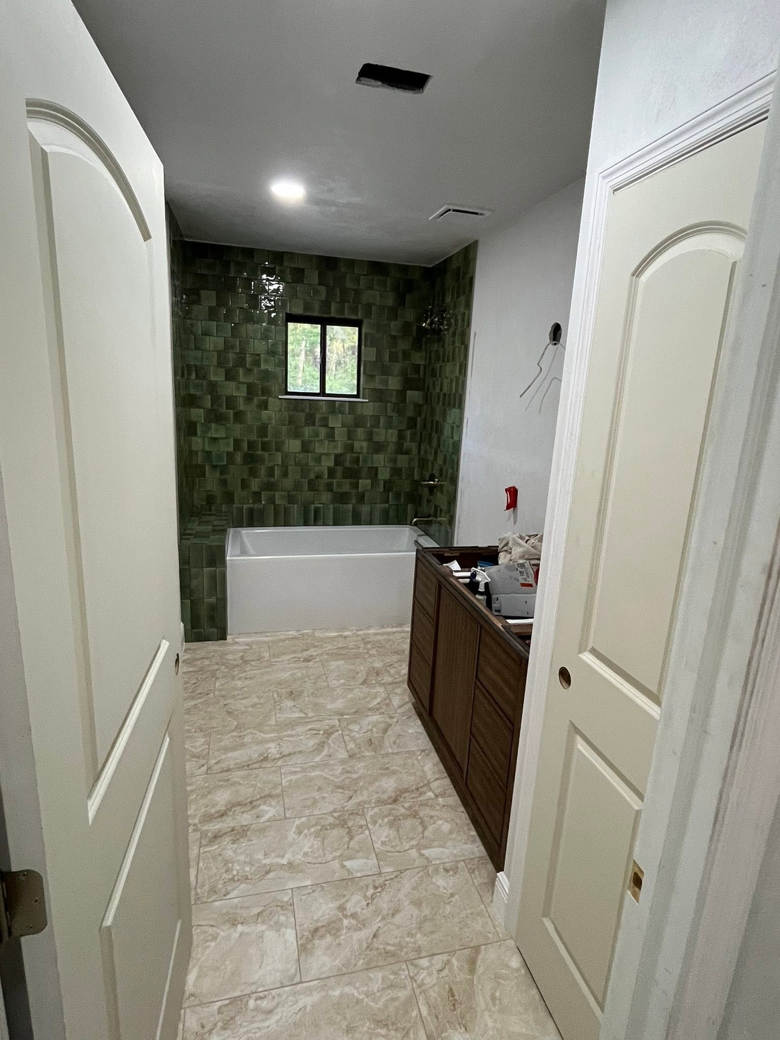 Remodeled bathroom after with green tile accent wall and new tub