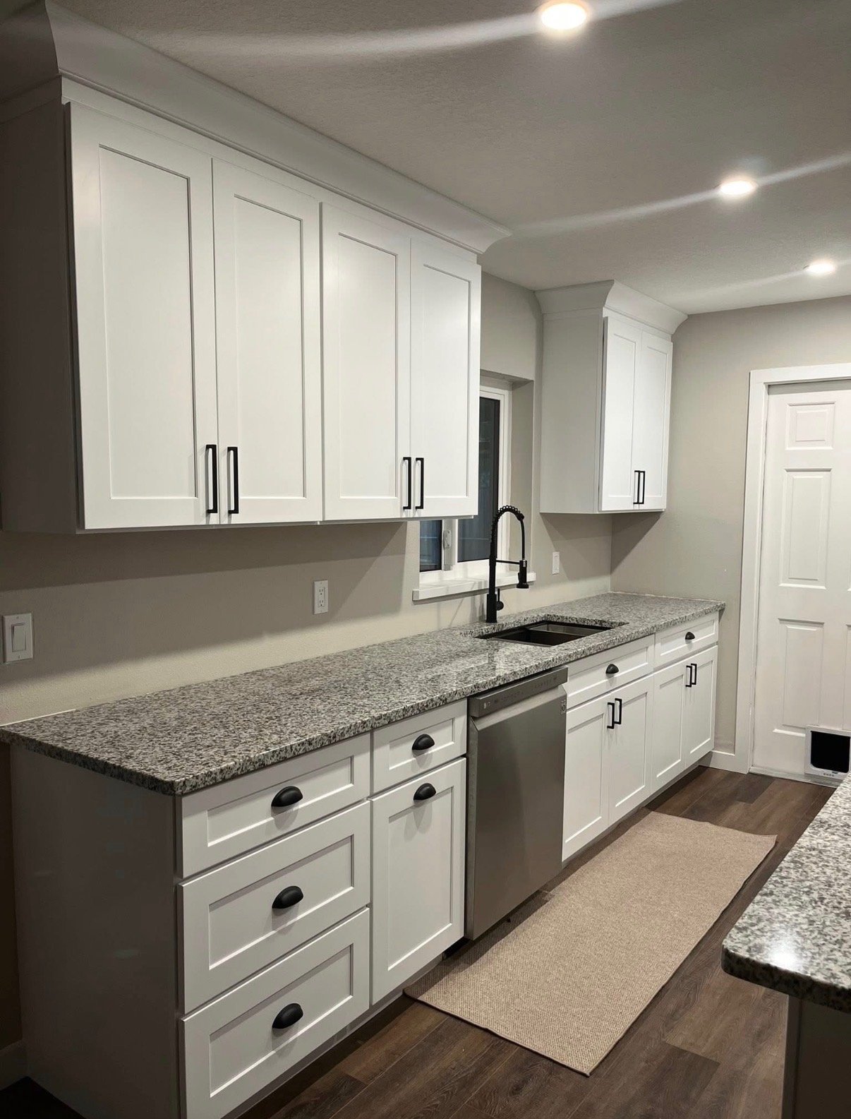 Close-up of white cabinetry with granite countertops and sink