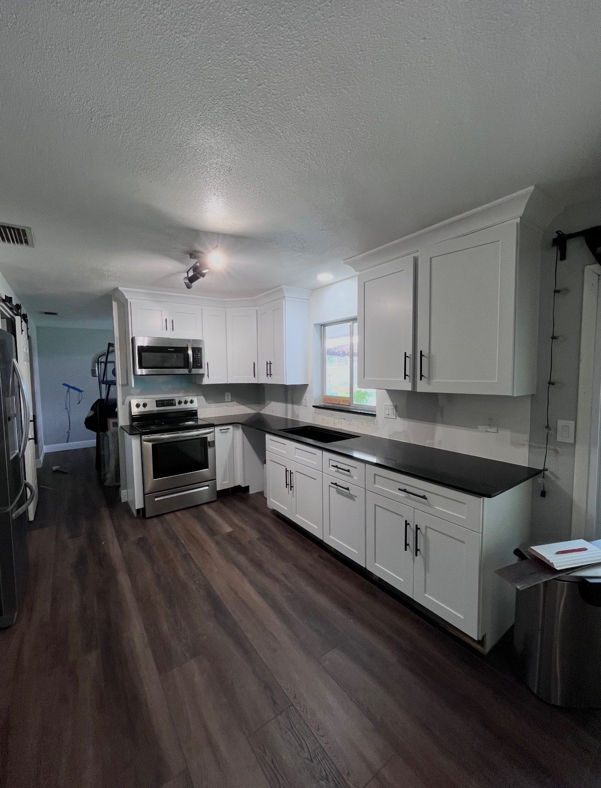 Kitchen cabinetry with black countertops and stainless appliances