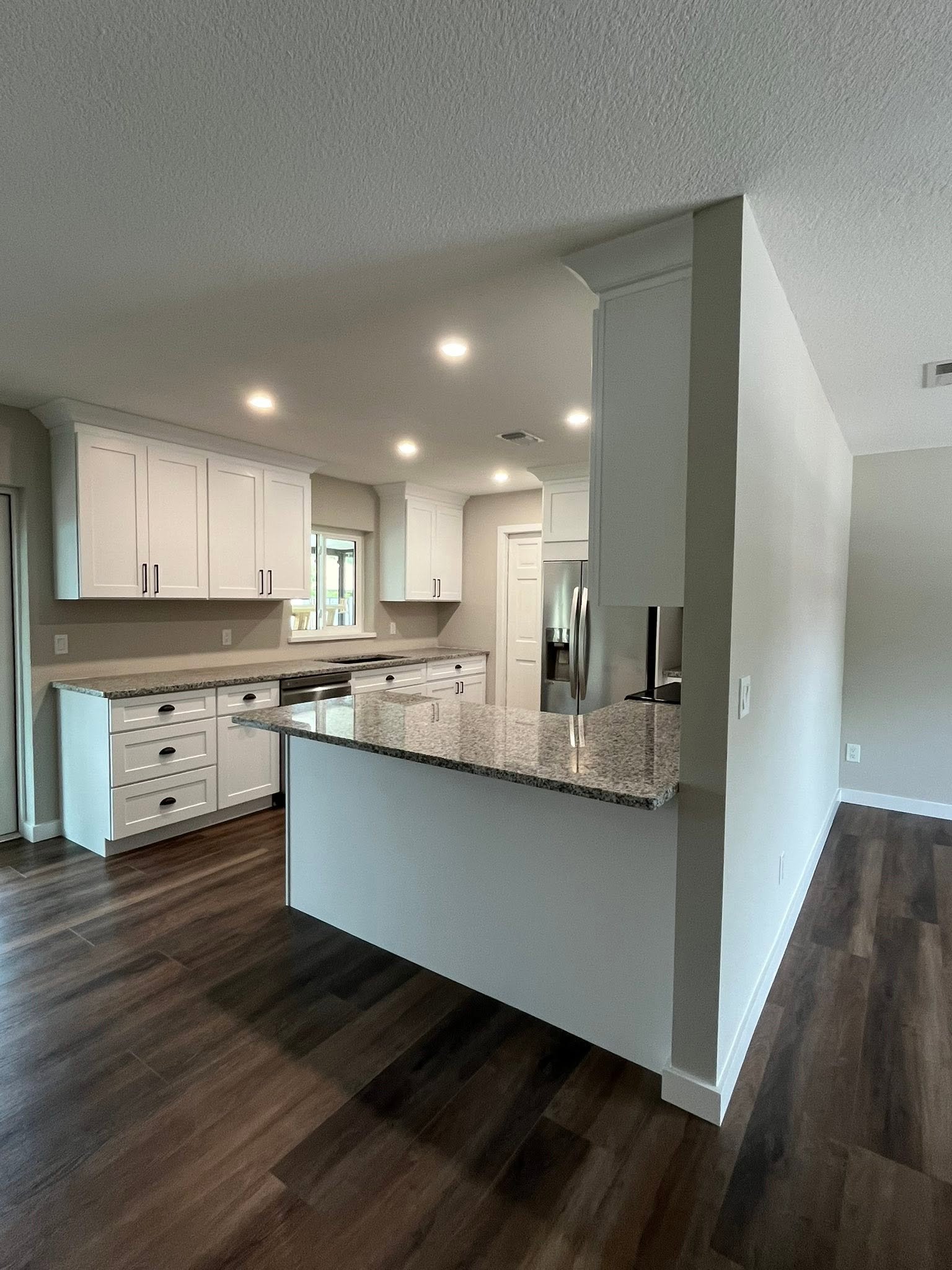 Remodeled kitchen with white cabinetry and granite island