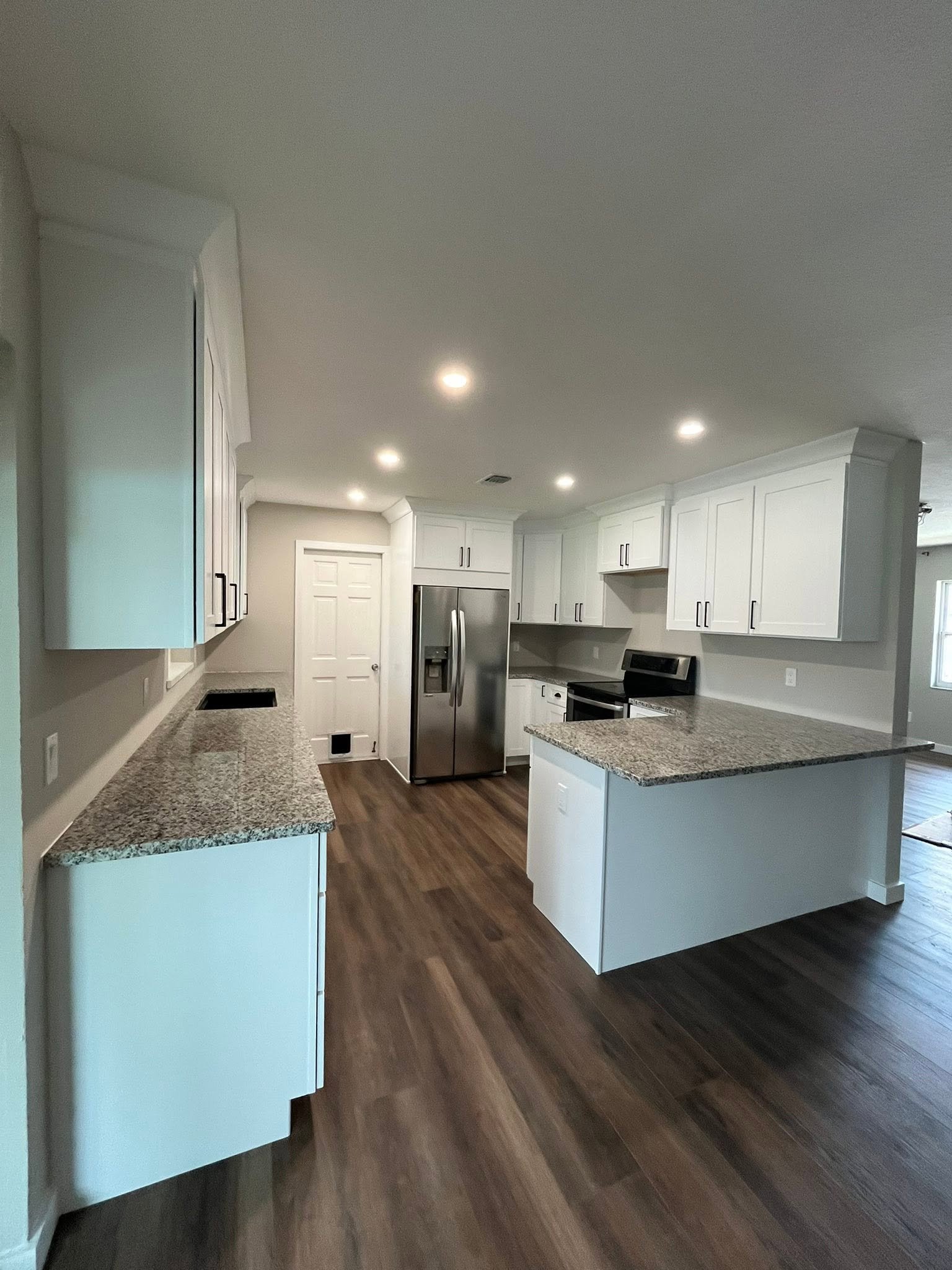 Remodeled kitchen with cabinetry, granite counters, and island