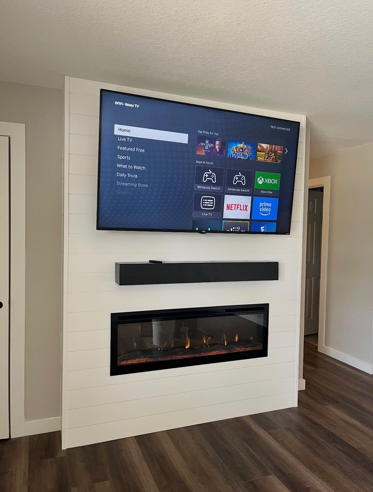 Built-in media wall with shiplap, mounted TV, and fireplace